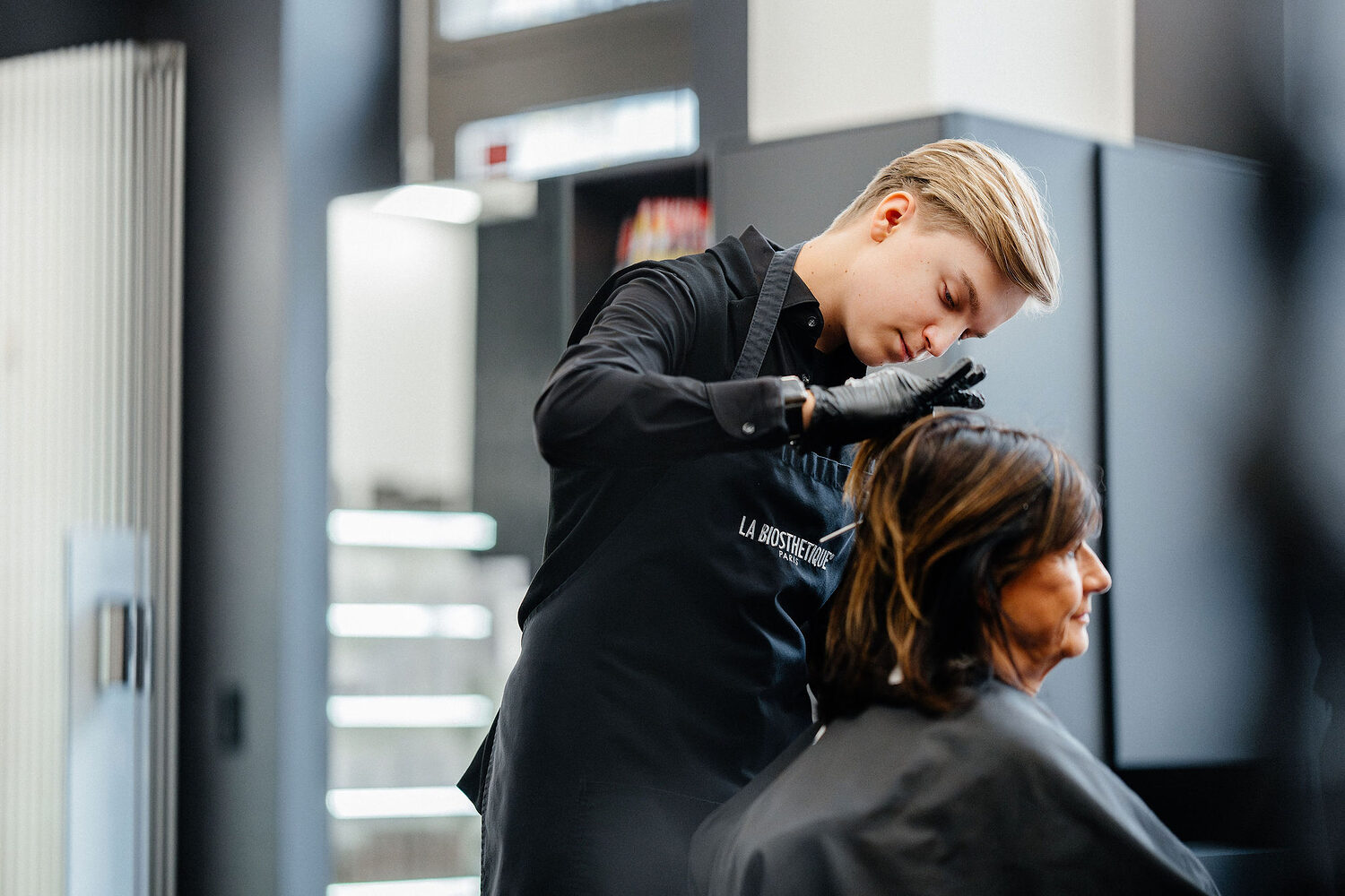 Friseurin frisiert eine Kundin im Salon